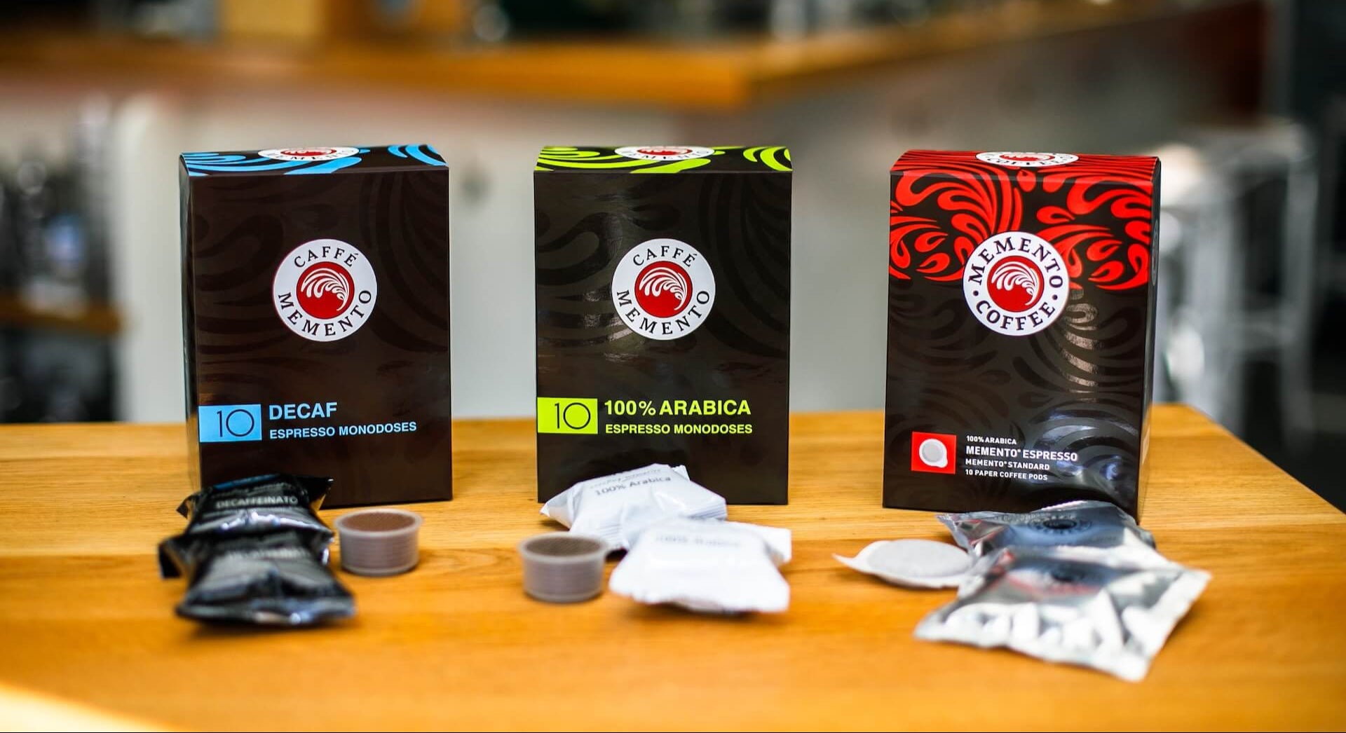 Three coffee packages on a wooden surface with a blurred background